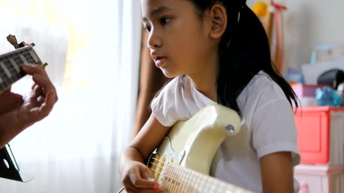 父亲教亚洲小女孩用电吉他学基本吉他初学者乐器自学在家学习，快乐家庭弹吉他