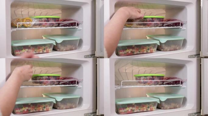 一个女人在真空的冰箱里得到玉米。冷冻蔬菜和水果，蘑菇，混合物，汤制剂。家庭烹饪用半成品。