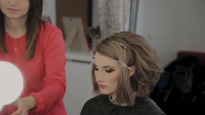 专业美发师为拍摄照片做女孩的发型