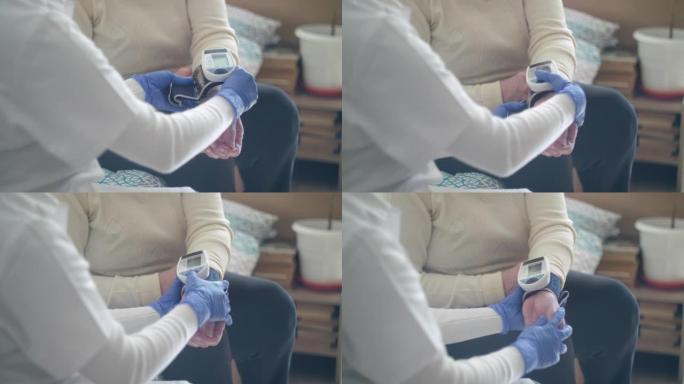 家庭护理员。一位医生对一位高级女性进行血压测量的特写镜头。在新型冠状病毒肺炎大流行期间，医生在她的家