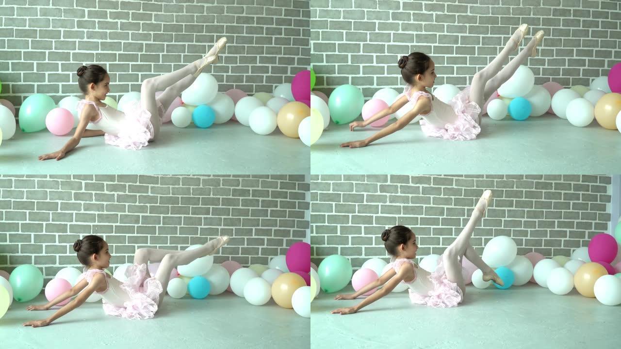 4k视频选择性聚焦实时中镜头美丽的小芭蕾舞女演员穿着粉色芭蕾舞紧身衣和芭蕾舞短裙坐在地板上通过移动手