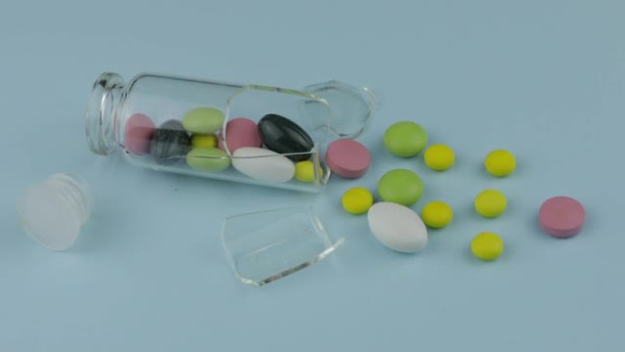 碎玻璃罐子，有许多不同的药丸和药物在蓝色背景上旋转