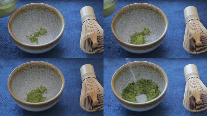 男子在蓝色表面的碗里准备绿茶抹茶。饮料是抗氧化剂和多酚的丰富来源。