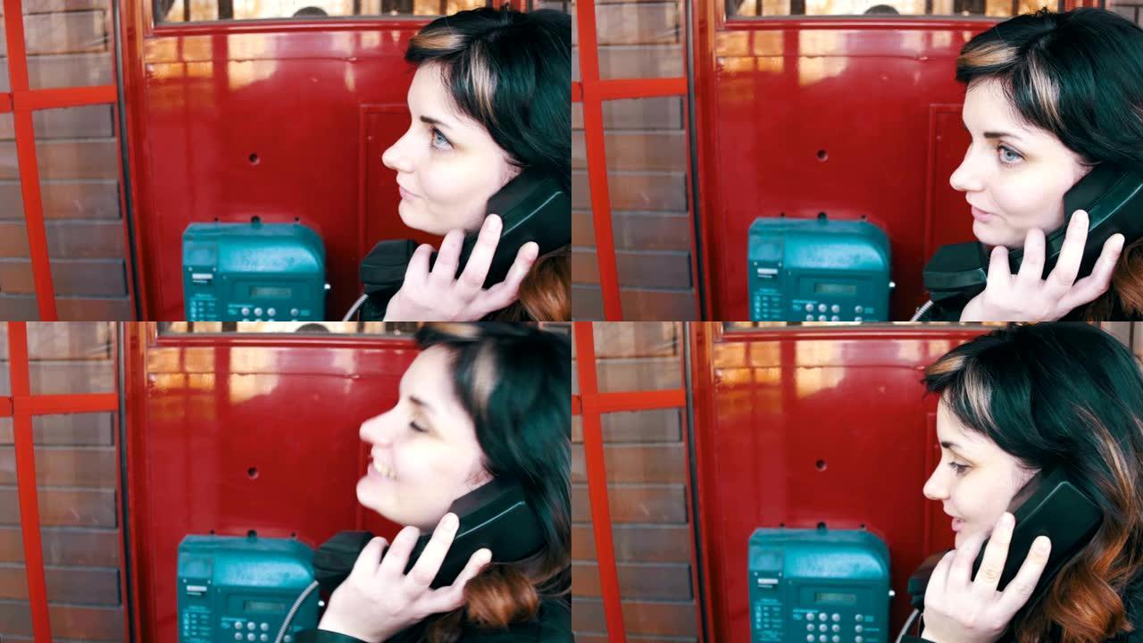 红色电话亭里的快乐女孩在街上打电话