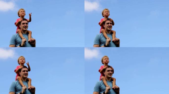 孩子坐在父亲的肩膀上，面对蓝天