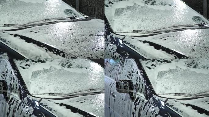 洗车。洗车机洗车。汽车上覆盖着白色的洗涤泡沫。特写。