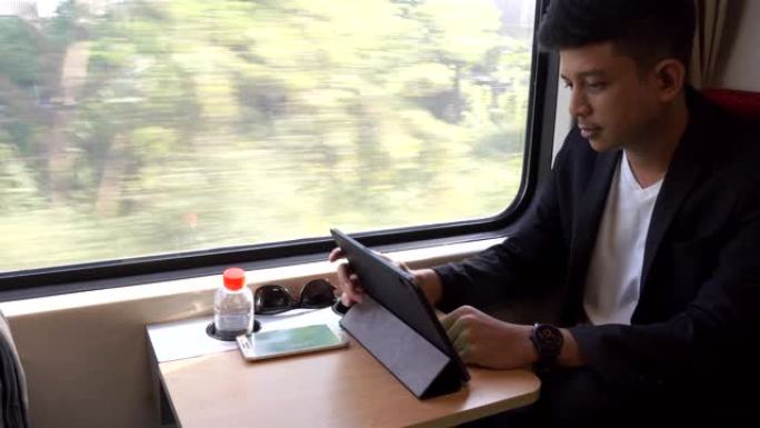 亚洲商人在火车上使用移动智能手机和数字平板电脑