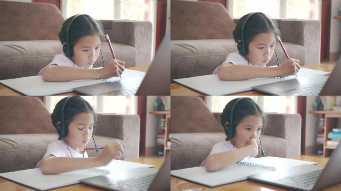 亚洲女童学生通过视频通话与老师在线佩戴耳机学习。由于Covid 19大流行，儿童在检疫期间用笔记本电