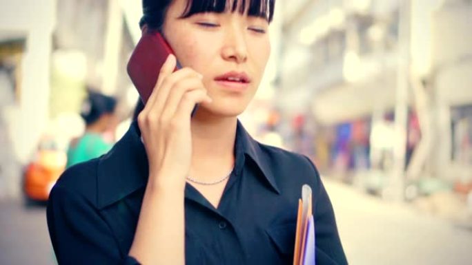 年轻的成年女商人在城市道路上白天使用智能手机。