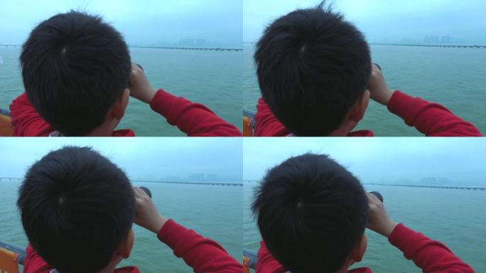 小男孩在游船上用双筒望远镜看