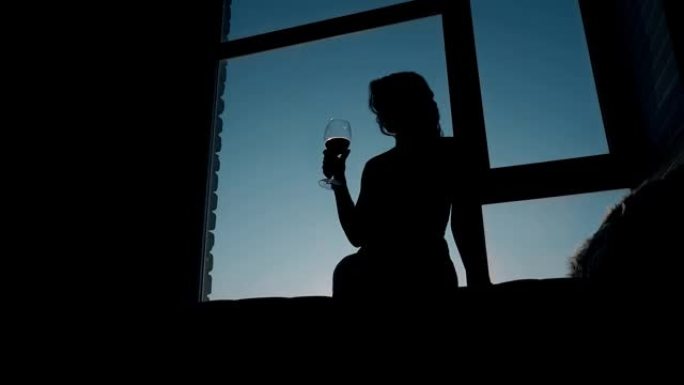晚上在窗洞喝酒的女孩的剪影