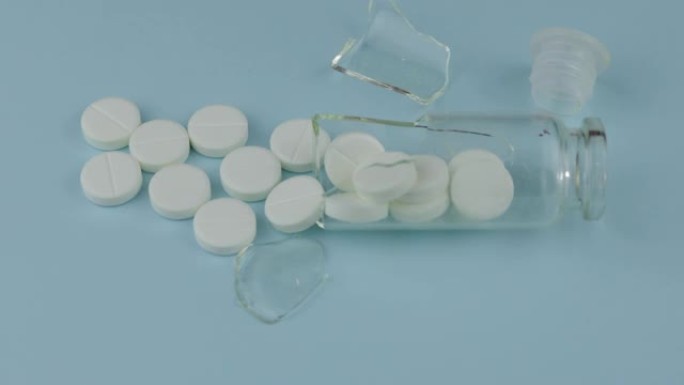 碎玻璃罐子里有许多药丸和药物在蓝色背景上旋转