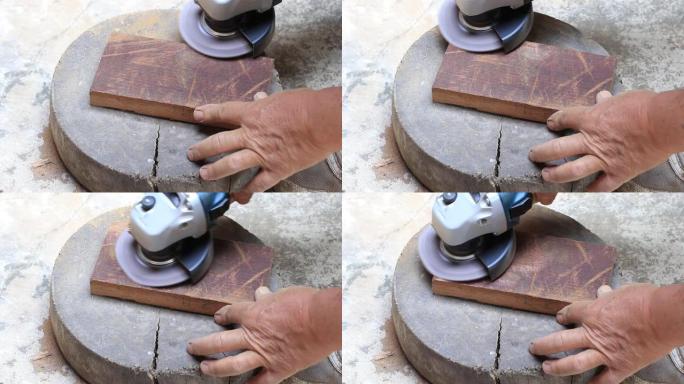 老工人手木匠的特写镜头等于在车间用随机轨道砂光机抛光木板，用电动工具打磨老式木制。