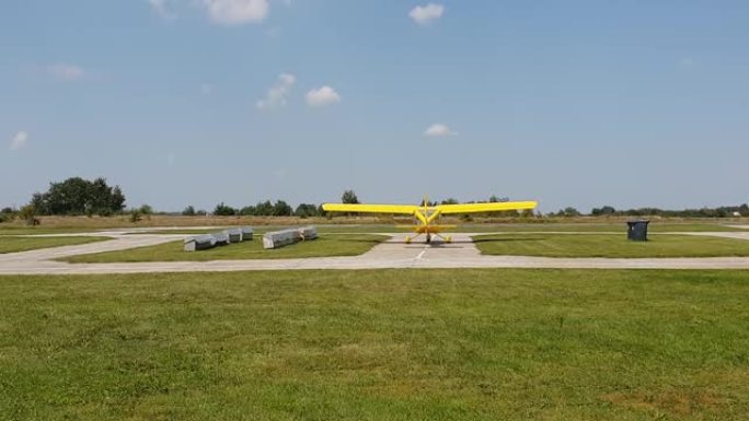 带螺旋桨的黄色飞机在机场的轨道上，螺旋桨正在工作，后视图