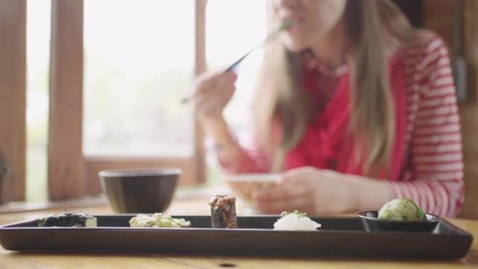 年轻的白人妇女在日本餐厅吃豆腐套餐。