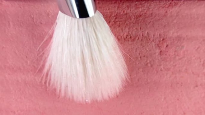 腮红刷在绒毛上获得粉红色的干颜料，可用于化妆。使用面部调色板的艺术家。美容行业的工作流程、工具细节。