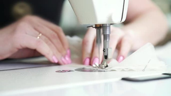 已婚妇女手在缝纫机上缝制布料的特写