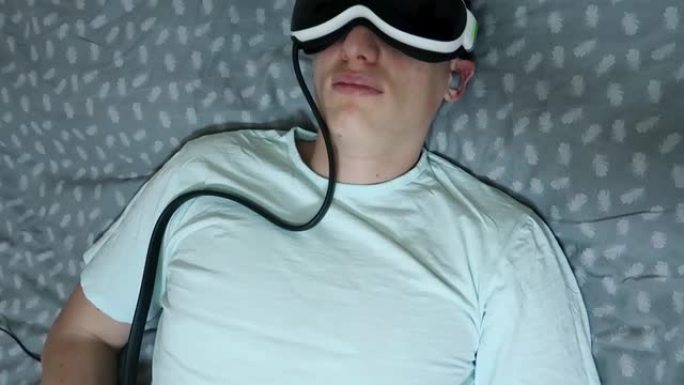 男子使用设备按摩器眼睛和头部，缓解乏力，放松，在笔记本电脑工作后休息