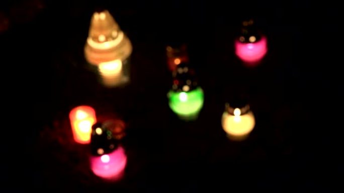 墓园晚上有五颜六色的蜡烛燃烧。焦点。4 k