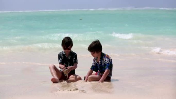 可爱的学龄前儿童，男孩，在海洋海滩上玩得开心。兴奋的孩子在毛里求斯玩海浪，游泳，快乐地嬉戏，享受家庭
