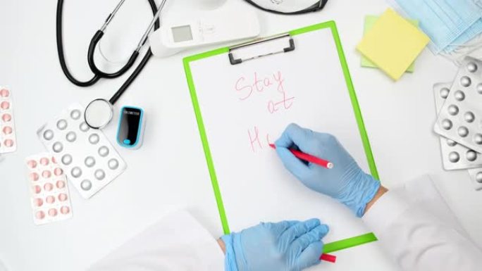 身穿蓝色乳胶手套和白色外套的医生用红笔在纸上写字呆在家里，在大流行和流行病中隔离的概念