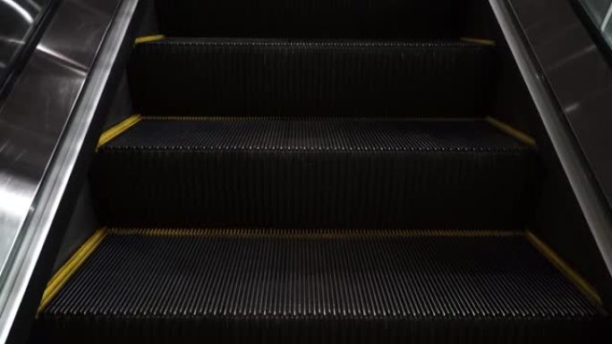 晚上空的移动楼梯跑下来的特写镜头。现代自动扶梯楼梯，可在室内移动。移动自动扶梯，机械师，电动。