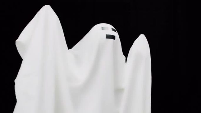 黑色背景上的白色床单。白色床单上的幽灵。万圣节的心情，恐怖和恐惧的性格。万圣节服装。