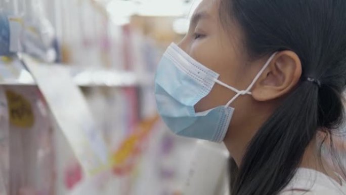 亚洲女孩戴着口罩，在新型冠状病毒肺炎前为家庭囤积食物，生活方式概念。