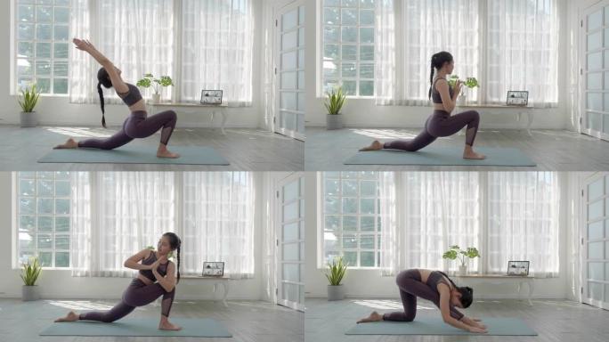在视频会议上，亚洲人与一群人在家中进行虚拟健身课。健身教练通过笔记本电脑上的视频通话进行在线瑜伽课。