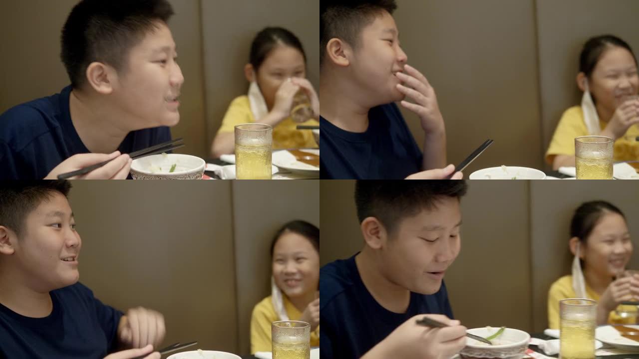 快乐的亚洲儿童与家人一起在餐厅吃寿喜烧，sha锅或火锅，生活方式理念。