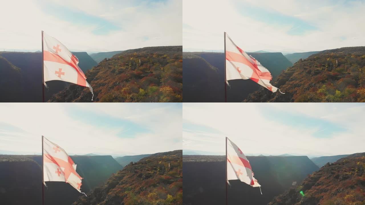 格鲁吉亚撕裂的旗帜在蓝色晴朗的天空背景下以慢动作挥舞。复古过滤器背景