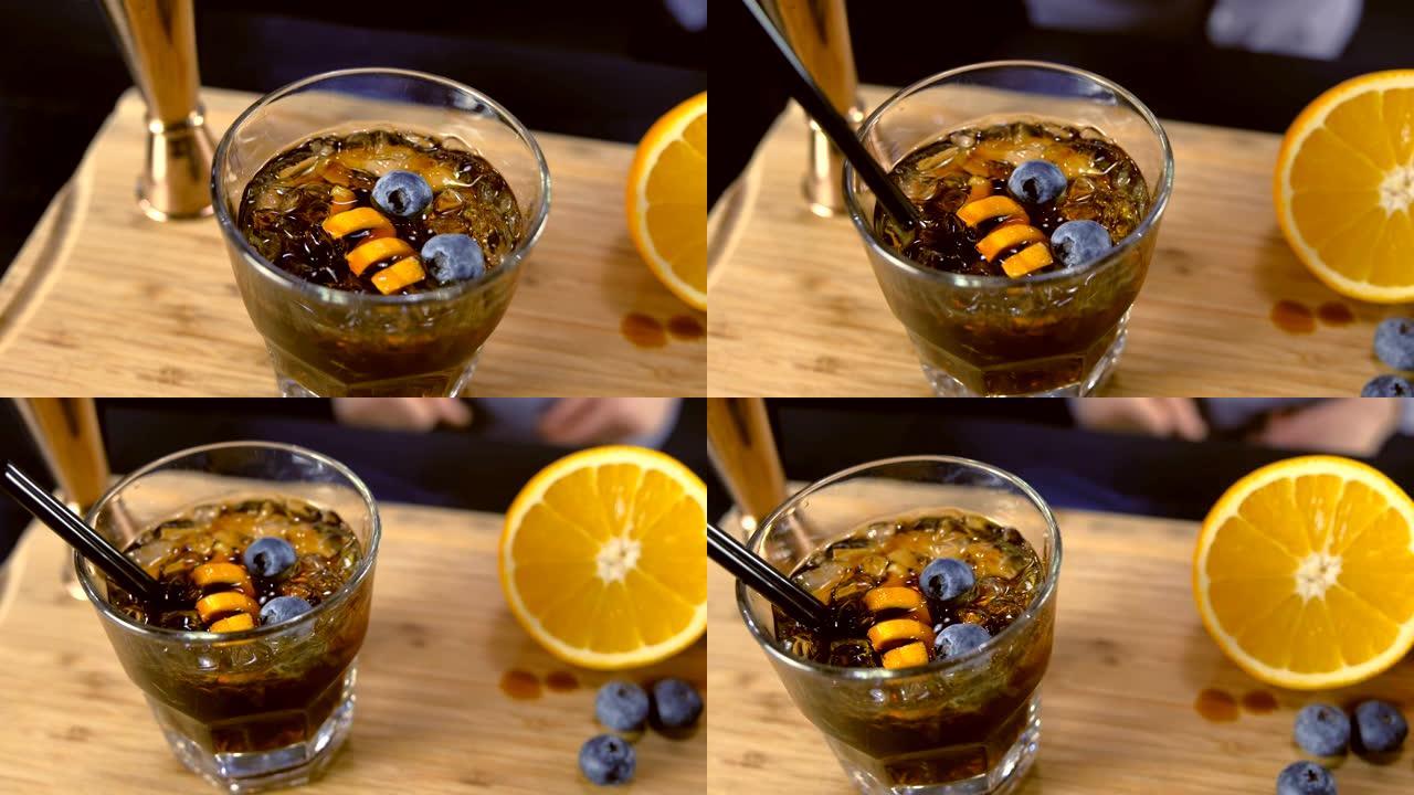 酒杯上的酒精鸡尾酒桌上有橙子、冰和蓝莓。