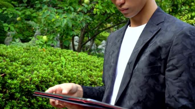 年轻的亚洲男子在户外使用大型平板电脑