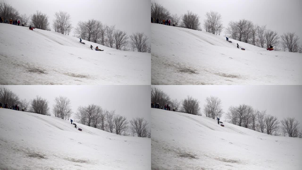 一群人骑在雪地滑梯上。孩子们在充气环上的冰滑梯上列出自己。雪橇、塑料溜冰场