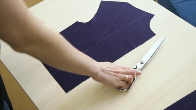 女裁缝手的上视图，将剪刀放在织物模板旁边