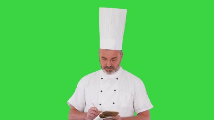 高级男厨师在绿屏上做笔记，色键