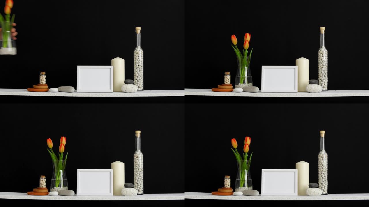 带相框模型的现代房间装饰。用装饰蜡烛、玻璃和岩石靠着黑色墙壁。用手把郁金香放在花瓶里。