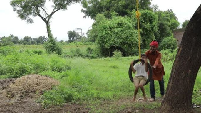 印度农民在绿地上与他的孩子玩耍