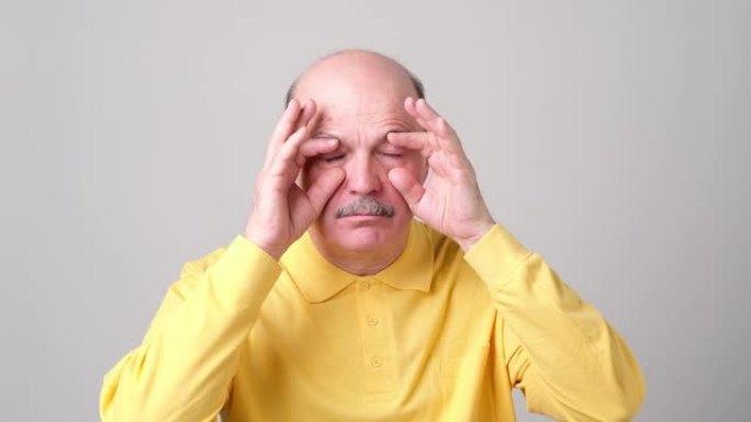 昏昏欲睡的老人试图用手指睁开眼睛。