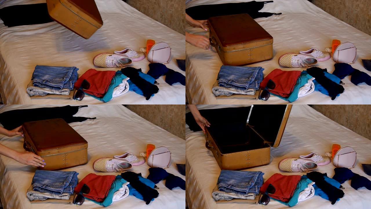 一个女人把一个棕色的老式手提箱放在床上，然后打开它。床上的衣服。快乐的trevels，度假概念。