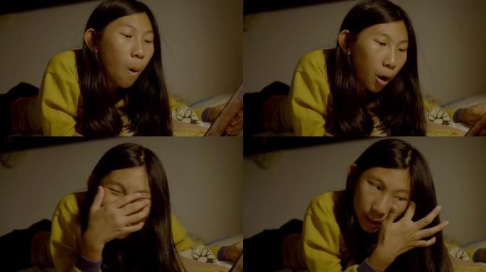 亚洲女孩穿着黄色毛衣躺在床上，晚上睡觉前看书，生活理念。