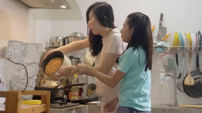 亚洲女孩自己学习烹饪食物，她的母亲有时总是支持和帮助生活方式。