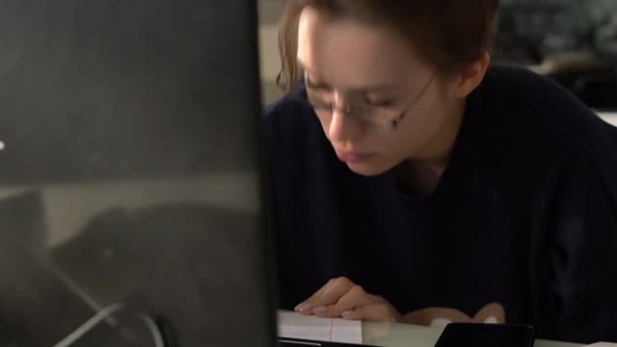 戴眼镜的女孩在笔记本电脑前仔细学习