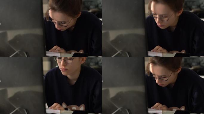 戴眼镜的女孩在笔记本电脑前仔细学习