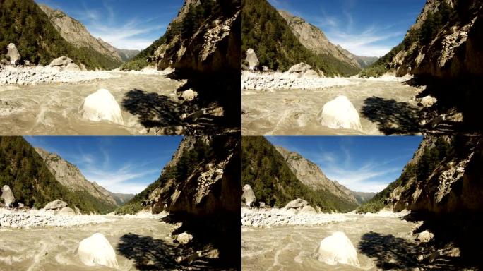 在高喜马拉雅山脉的石质峡谷恒河的河岸上的小修行所，从融化的雪和泥泉中涌出的棕色的水和蓝色天空中的卷云