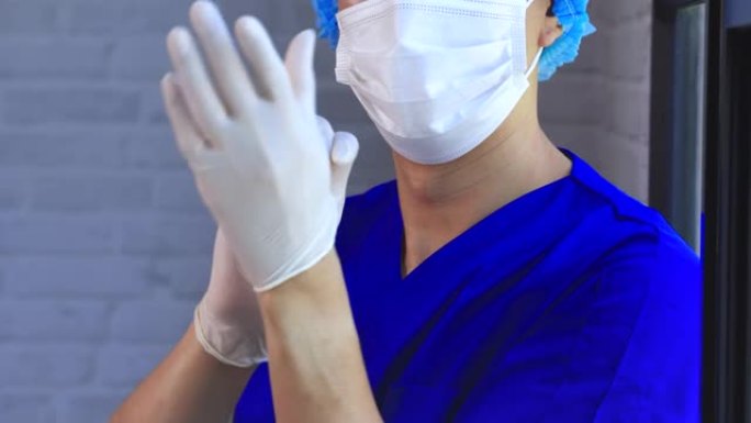 男医务工作者在工作中戴着乳胶手套、外科口罩、蓬松帽等防护装备。亚洲男子穿着和准备在医院工作