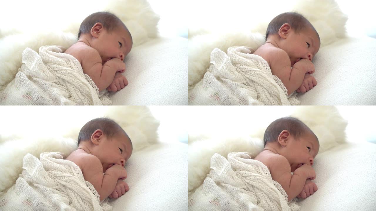 4k选择性聚焦侧视图中特写镜头亚洲女性新生婴儿躺在白色床上。可爱的蹒跚学步的婴儿用移动的头和手环顾四