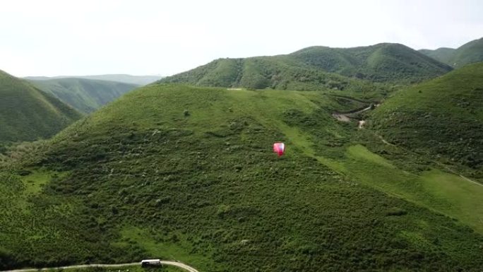 在山里滑翔伞。绿色的田野，山丘