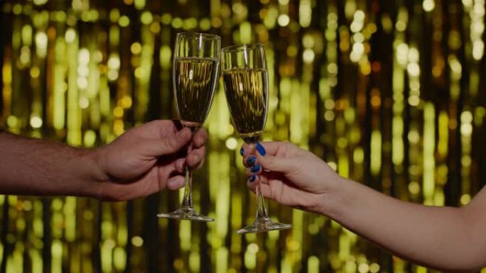 两只手与一杯香槟葡萄酒或鸡尾酒一起欢呼，在金色背景上举杯吐司