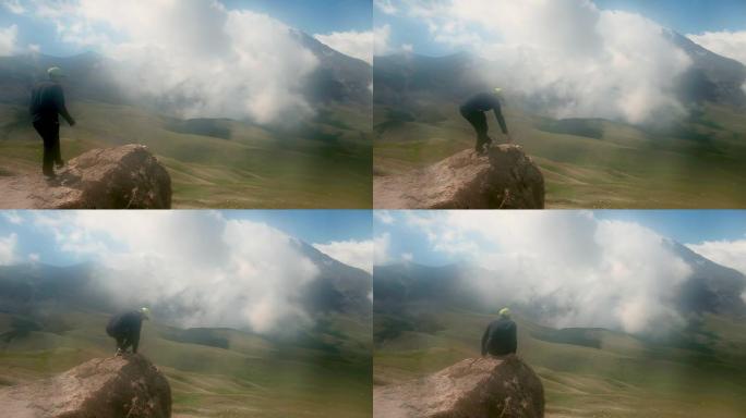 旅游生活方式。生存概念。游客坐在石头上。向远处挥手。徒步旅行。大雾，雨天，后视图。岩石，山脉。运动。